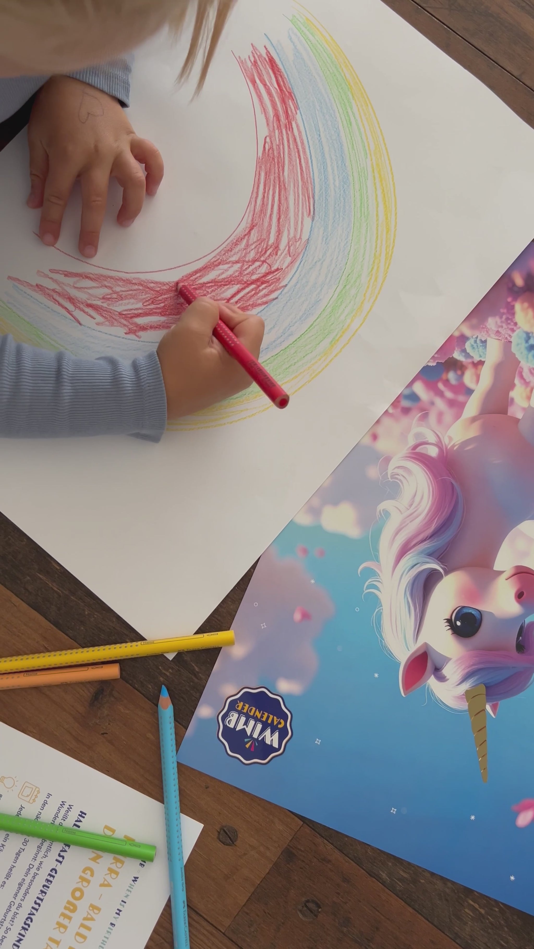 Kind malt Regenbogen neben dem Einhornkalender