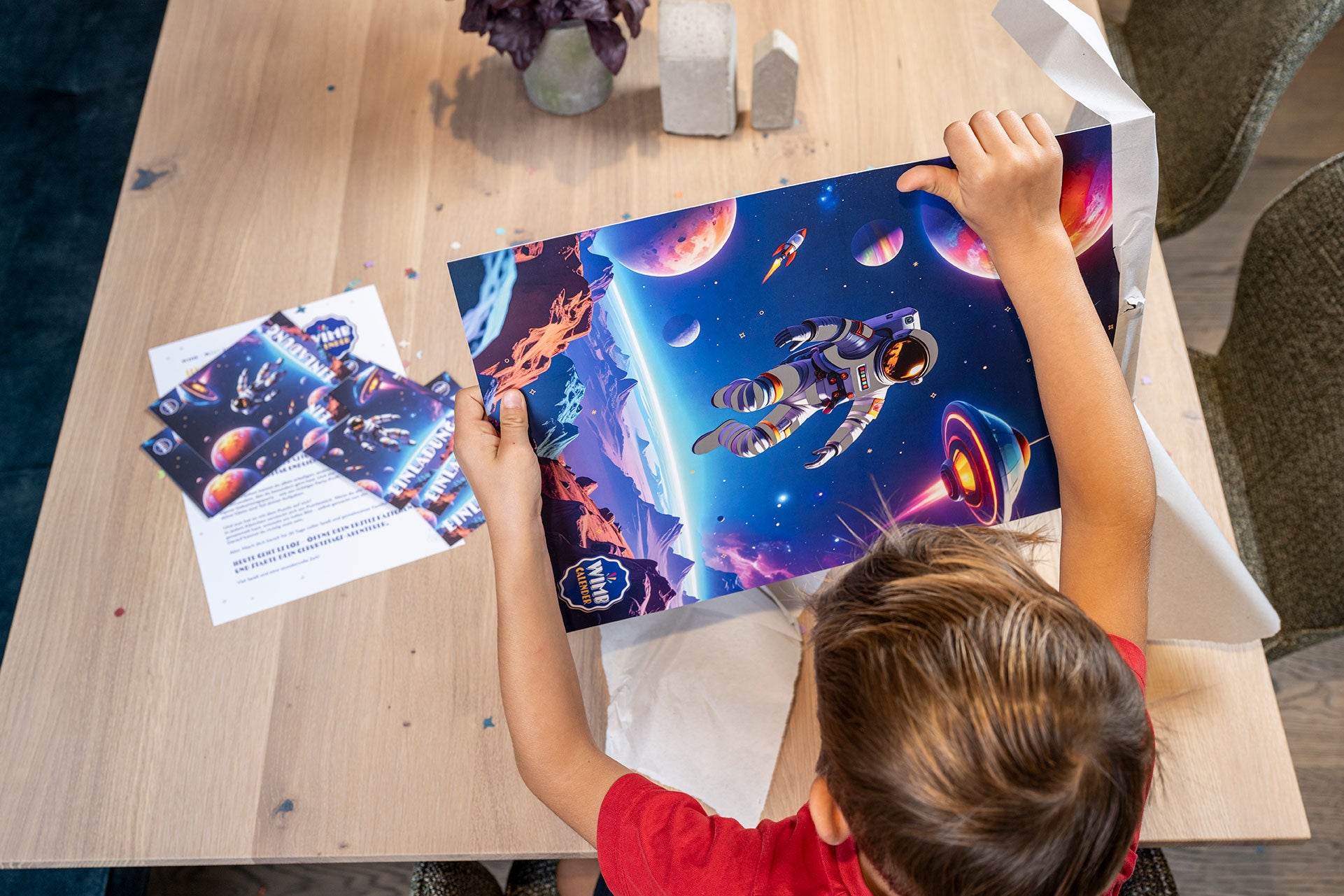 Kind betrachtet Astronaut-Kalender und Einladung auf dem Tisch