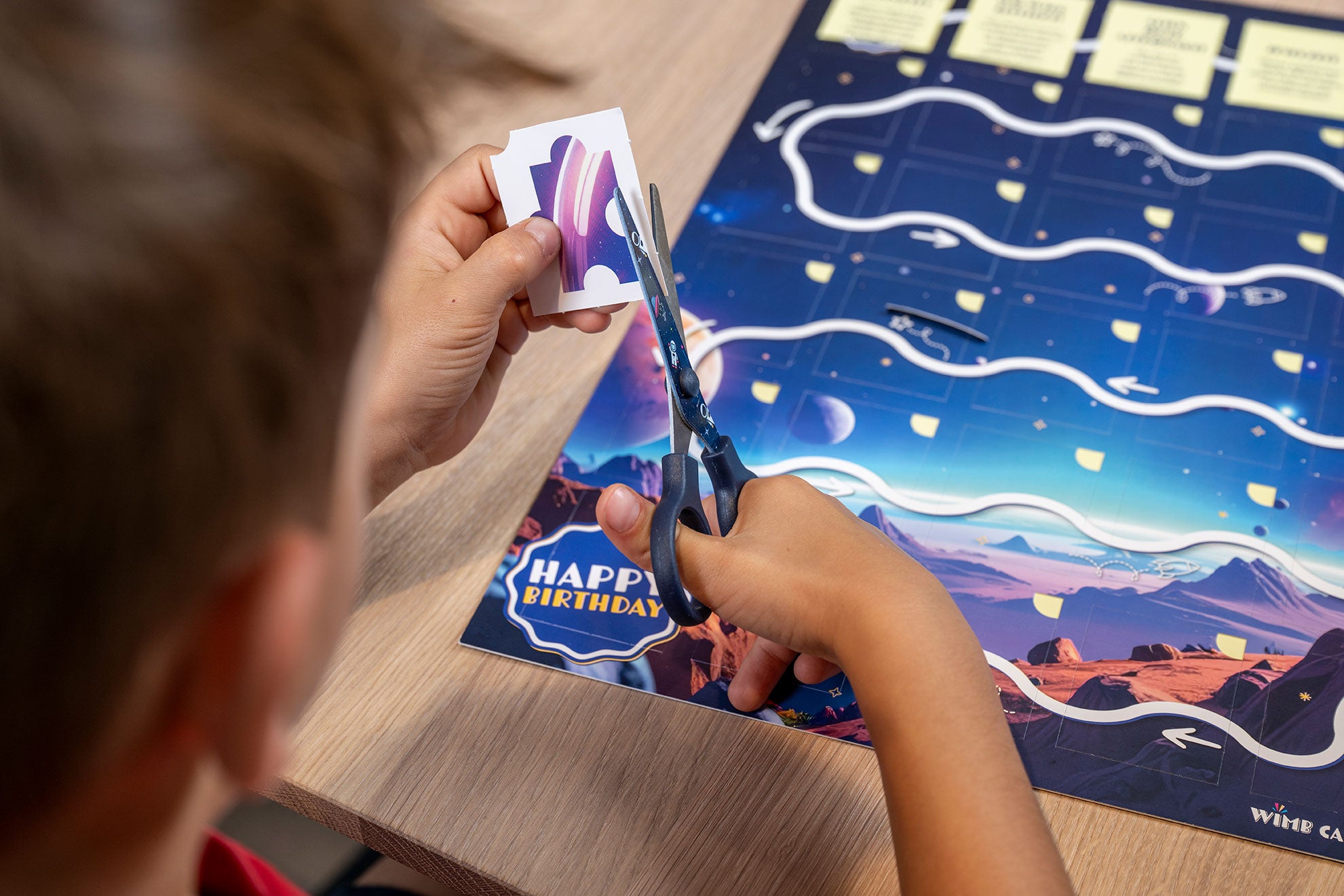 Kind schneidet ein Puzzlestück aus dem Astronauten-Kalender