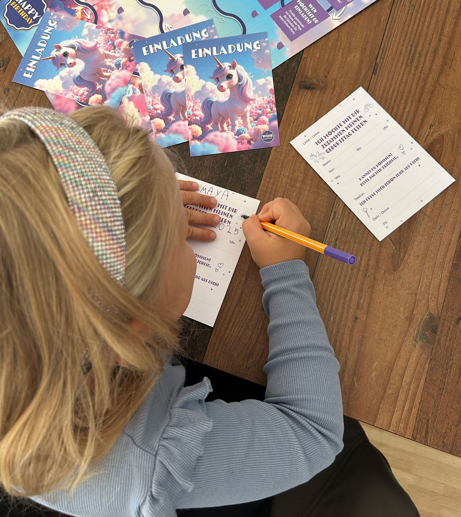 Kind schreibt Einhorn-Einladung, Kalender liegt daneben